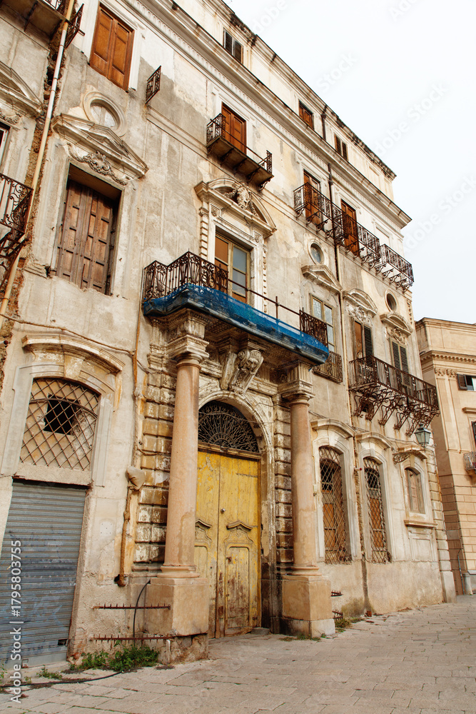 Fototapeta premium Rustic Old Town Facade With Iron Balcony, Weathered Shutters, and Aged Stonework