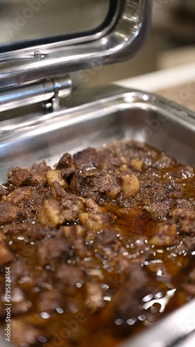 Shot of chicken chettichund curry placed on a buffet counter, featuring its rich, spicy gravy and bold South Indian flavors, presented warmly as part of a hotel or restaurant buffet setup.