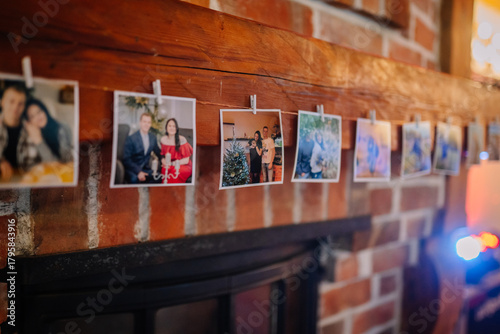 Photos Colorful collection of photographs hanging on a wooden beam above a cozy firepla