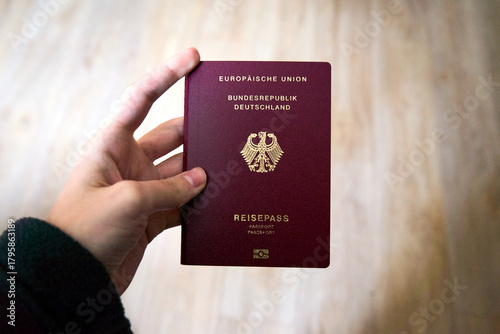 Fotografie deutscher Reisepass in einer weiblichen Hand vor einem hellen Hintergrund