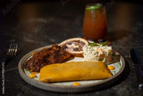 Venezuelan Christmas dish: hallaca, ham bread, chicken salad and pork leg, accompanied by a glass of iced tea with a slice of lemon.