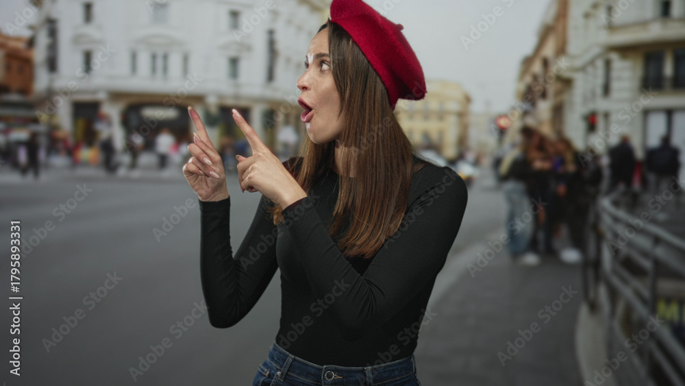 Fototapeta premium Woman points both index fingers upward on city street wearing red beret and black shirt; surprise curiosity.