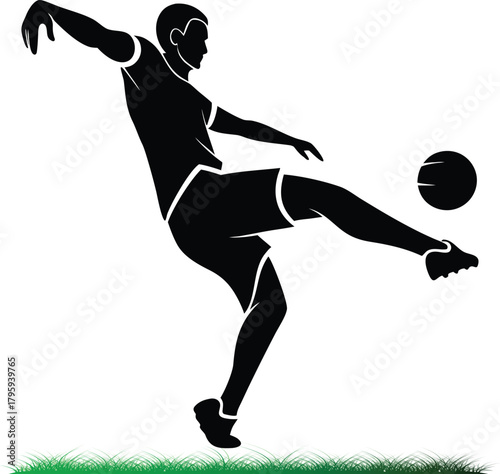 Silhouette of soccer player kicking ball on green field