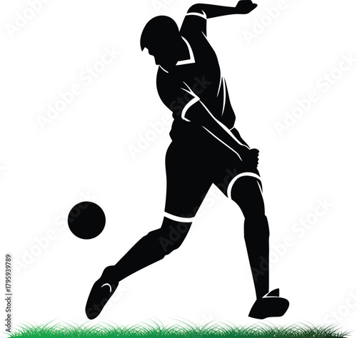 Silhouette of soccer player kicking ball on green field