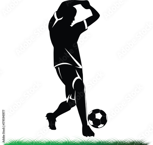 Soccer player silhouette kicking ball on green grass field