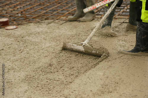 Construction worker leveling freshly poured concrete in a building foundation