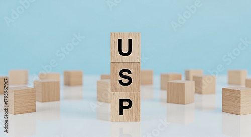Wooden blocks spelling usp on a white surface against a blue background representing unique selling proposition and business strategy concept