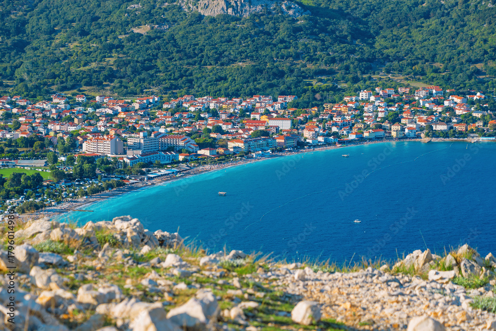 Naklejka premium Coastal town with vibrant blue sea and lush green hillside. Baška, Krk island, Croatia