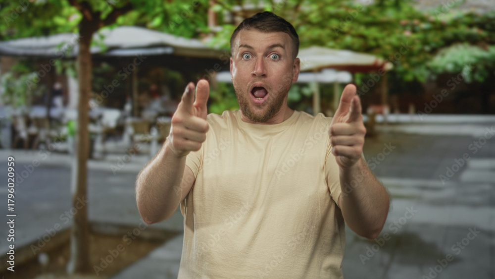 Naklejka premium Man raising clenched fists with bare forearms and open mouth cheering on a sunny street cafe terrace with umbrellas and trees; victory joy.