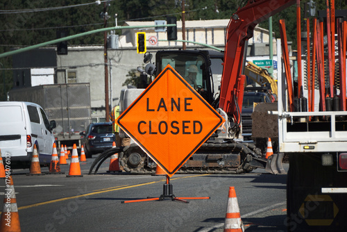 Road work and traffic with lane closed sign on street.