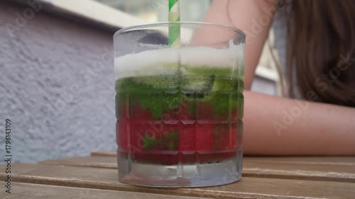 Iced matcha drink with strawberry syrup in a glass - layered beverage close-up