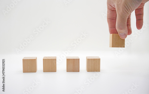 Hand Placing Wooden Block on White Background