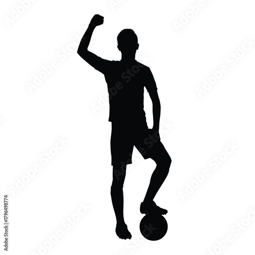 Silhouette of a football/soccer player standing in shorts and cleats, with one foot on the ball and a fist raised in triumph. Represents winning, success, sport, and celebration.