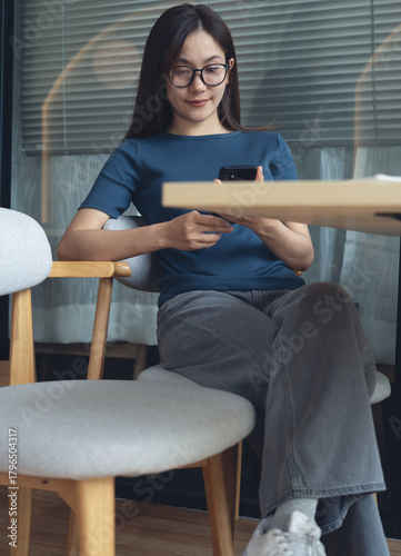Close up, young asian woman sitting at table using mobile phone for online shopping, digital banking and social networking via mobile app at coffee shop, online messaging, vertical