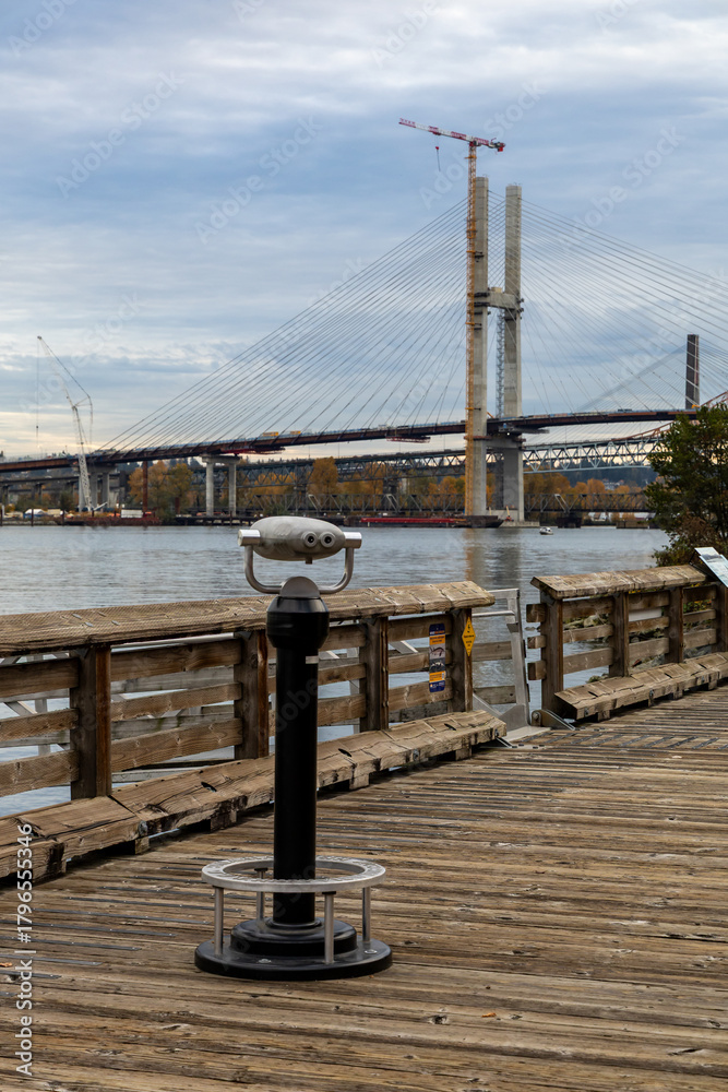 Fototapeta premium Public Pier With Binocular Viewer Over the River, Construction Bridge in New Westminster, BC