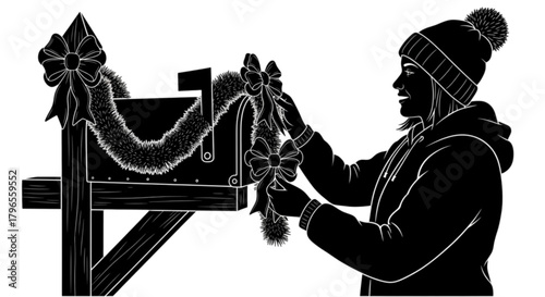 Woman in winter clothing decorating a mailbox with festive garland and bow.