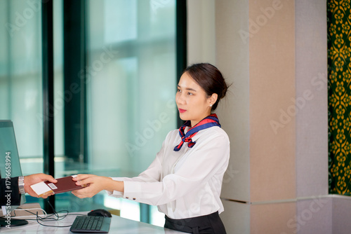 Airport groud staff receive passenger;s passport on check in counter to checking for travel with airplane.
