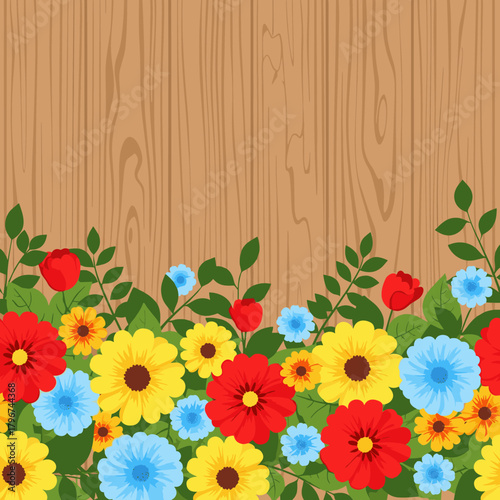 A vibrant collection of colorful flowers and green leaves adorning a wooden background.