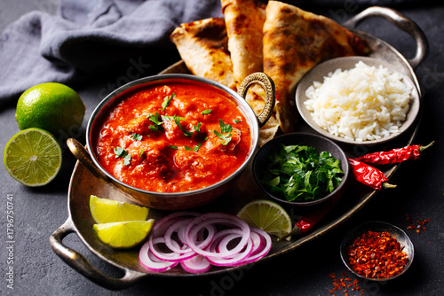 Authentic Indian feast: chicken tikka masala with rice, naan, lime and spices. Grey background. Close up.