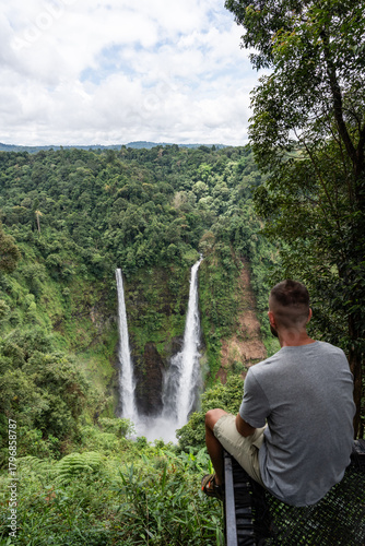 Fotografija Man observing Tad fane twin waterfalls flowing in lush jungle