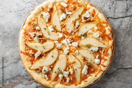 Honey pear pizza with blue cheese, nuts, mozzarella and thyme close-up on a wooden board on the table. Horizontal top view from above