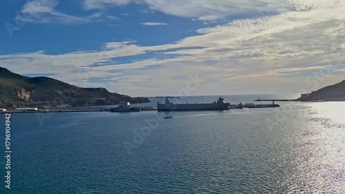 spain murcia jan 4 2024 Harbor View With Docked Ships, Calm Sea And Bright Blue Sky Over Rocky Hills