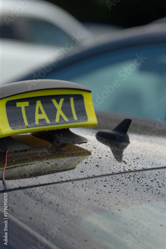 Closeup of taxi sign on wet roof, Reflected taxi indicator against textured urban parking surface, Detailed view of taxi sign reflected on moist rooftop with textured background and bokeh