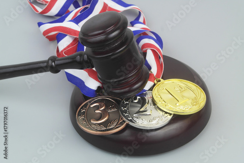 Wooden judge gavel and gold, silver and bronze  medals on grey background.