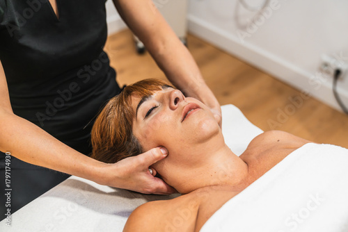Photos Professional therapist performing physiotherapeutic massage on a woman's jaw and
