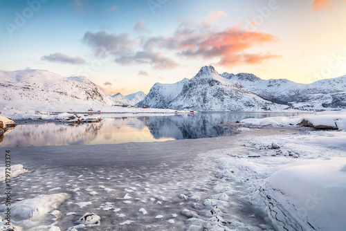 Flakstadpollen and Boosen fjords with cracks on ice during sunrise with Hustinden mountain on background.