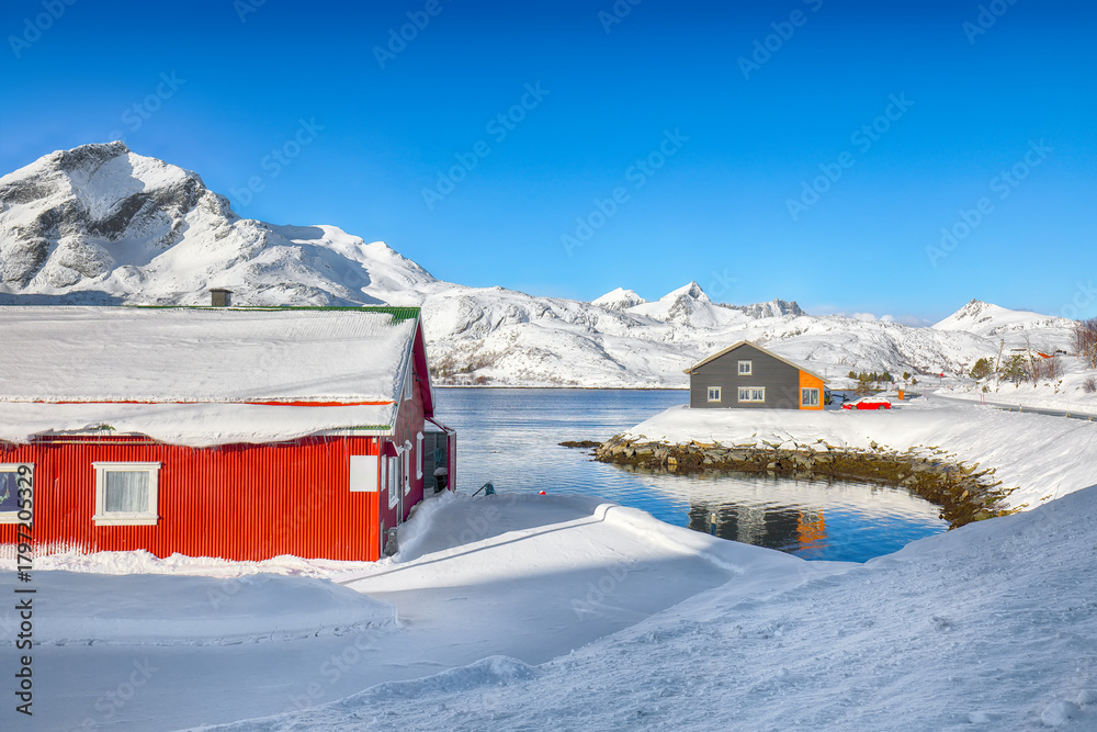 Naklejka premium Amazing scenery with traditional Norwegian red wooden houses on the shore of Sundstraumen strait.