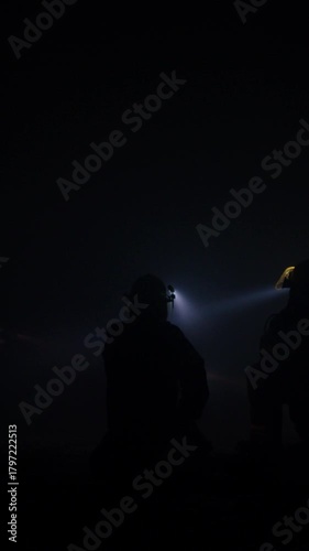 Rescue forces search for survivors inside a dark tunnel using flashlights