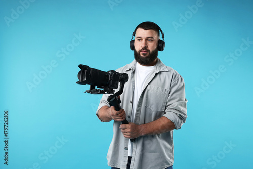 Obraz na plátne Videographer using gimbal stabilizer with camera on light blue background