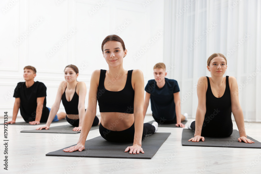 Naklejka premium Group of people doing stretching exercise on fitness mats in gym