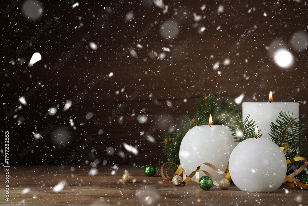 Fototapeta premium Christmas composition with burning candles on table under falling snow. Greeting card