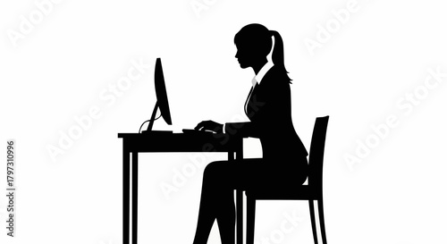 Silhouette of a businesswoman working on a computer at her desk.