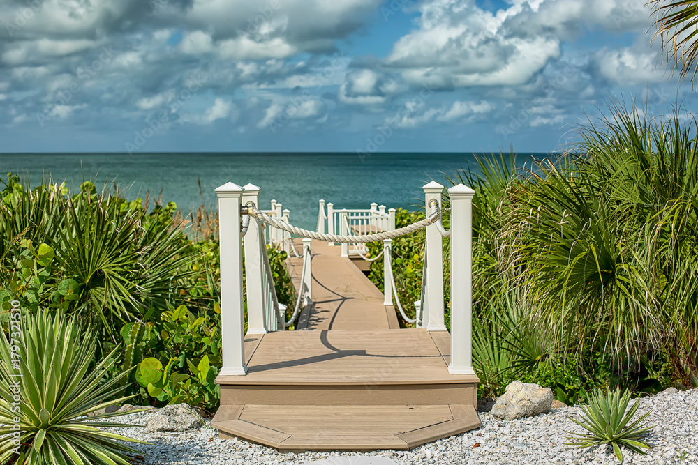 Fototapeta premium Wood boardwalk with white rope fence entrance to beach 