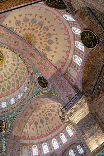 Interior view of a mosque with intricate dome and colorful decorations
