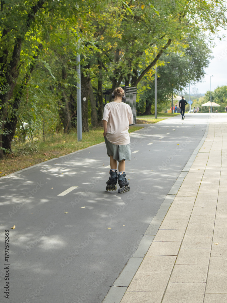 Obraz premium Person rollerblading on a park path active leisure vertical