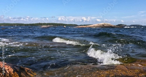 Landscape view of rocky seashore at Pirttisaari nature reserve with waves crashing on shore in sunny summer weather with clouds in the sky, Pirttisaari, Porvoo, Finland. 