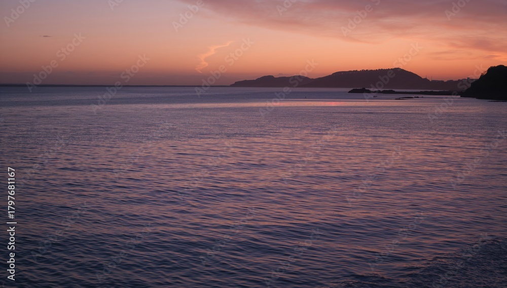 Obraz premium Sunlight reflects on calm water at dusk with a dark silhouette of the shoreline, tranquility of nature