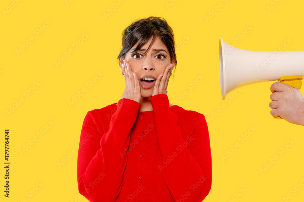 Naklejka premium Woman in red sweater reacts to loud speaker on bright yellow background
