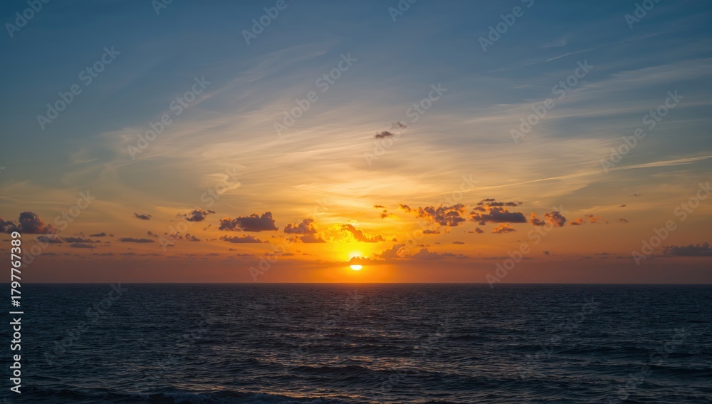 Fototapeta premium Hued clouds create a vivid sunset over the ocean horizon, seasonal change