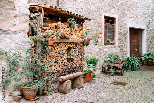 Fototapeta Naklejka Na Ścianę i Meble -  Cozy rustic street corner in a small European village featuring weathered wooden shutters, stone walls, and decorative flower pots.
