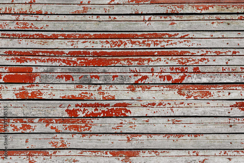 Weathered wooden planks with peeling red paint, horizontal lines create rustic texture. Concept of vintage decay