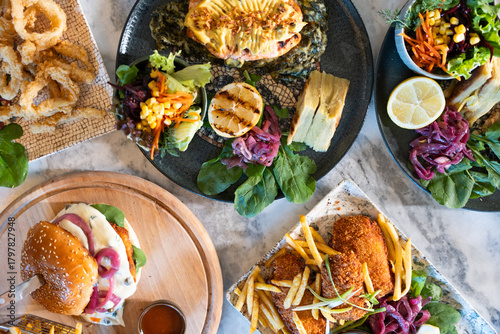 Canvas Print Close-up shot of a juicy gourmet burger on a rustic wooden table, surrounded by