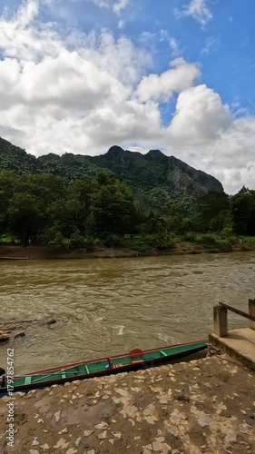 A strong, flowing river in Vang Vieng, Laos, filmed from a quiet riverbank, capturing the natural power and peaceful atmosphere of this scenic destination.
