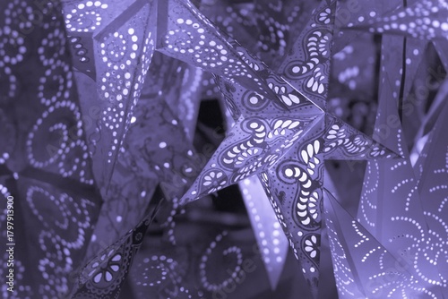 Colorful purple xmas lantern stars at christmas market season. Beautiful shiny star mood lamp in merry advent decoration. Traditional symbol of the best miracle time of the year. Part of series