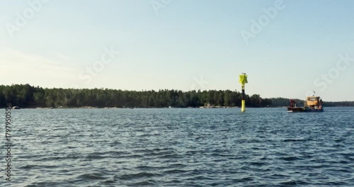 A small cargo barge passing throught the sea in sunny summer weather, Sipoonselkä, Sipoo, Finland.