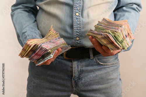 Both hands grasp heavy bundles of banknotes Ukrainian currency. symbolizing financial accumulation, large cash amount and economic activity. cash money ukraine.